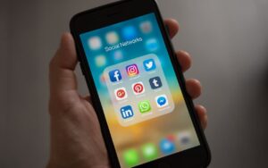 Osoba drži telefon na čijem ekranu je otvoren folder sa društvenim mrežama