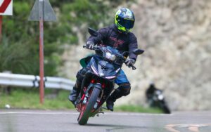 Motorista sa kacigom i zaštitnim odelom vozi motor.