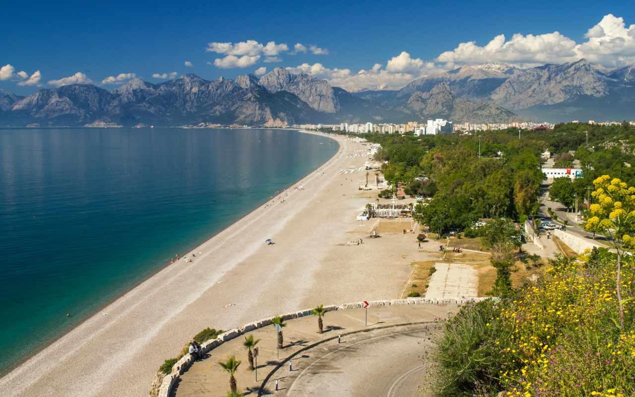 Plaža okružena šumom i planinama.