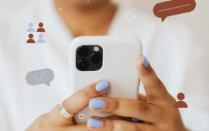 Devojka drži telefon oko kojeg su nalepljeni stikeri oblačića za dopisivanje