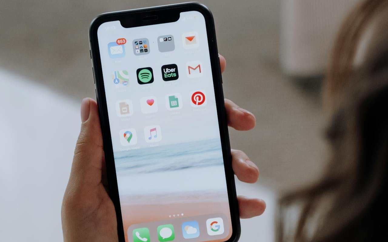 Devojka drži telefon na kojem se vide aplikacije