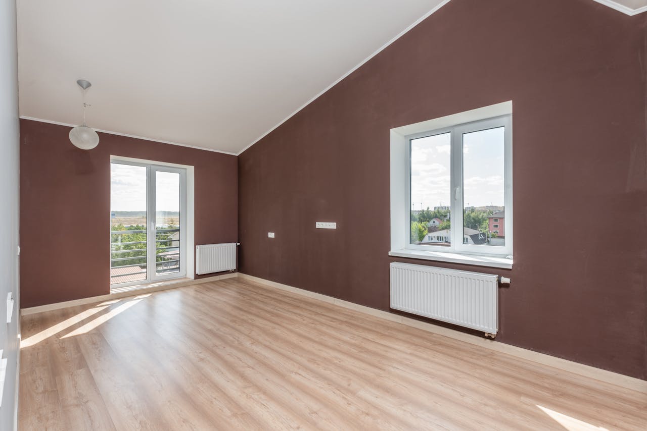 Renoviran prazan stan sa braon zidovima, belim prozorima i belim radijatorima