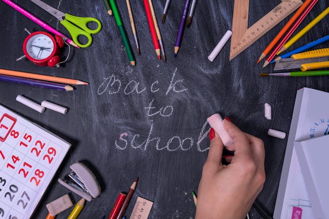 Ruka piše kredom na crnoj tabli back to school.
