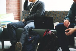 Momci sede na dvosedu dok jedan od njih radi na laptopu